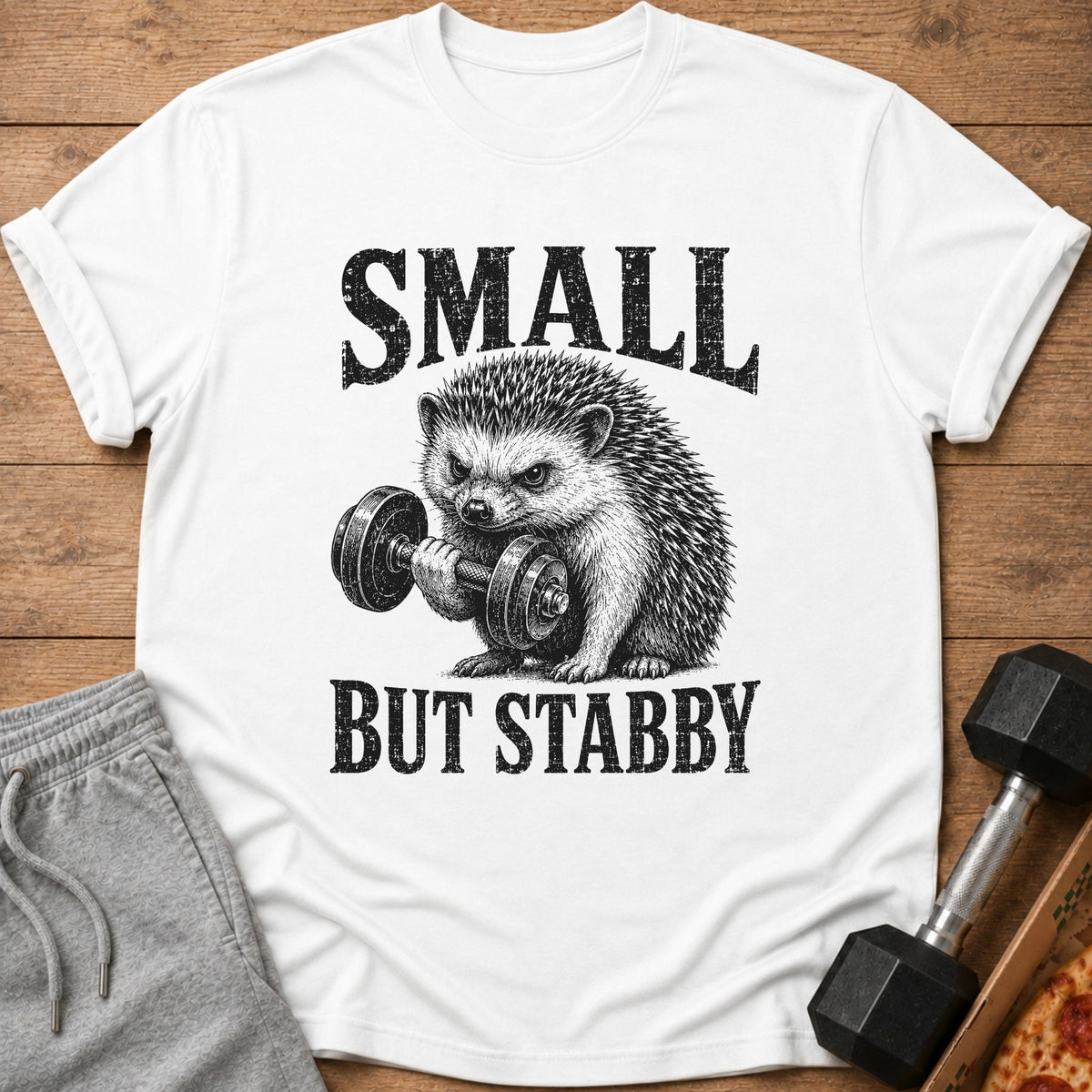 White t-shirt with a graphic of a hedgehog lifting a dumbbell and the text "SMALL BUT STABBY."