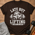 Brown t-shirt with a sloth on a barbell graphic and text "LATE BUT LIFTING COUNTS THE SAME".