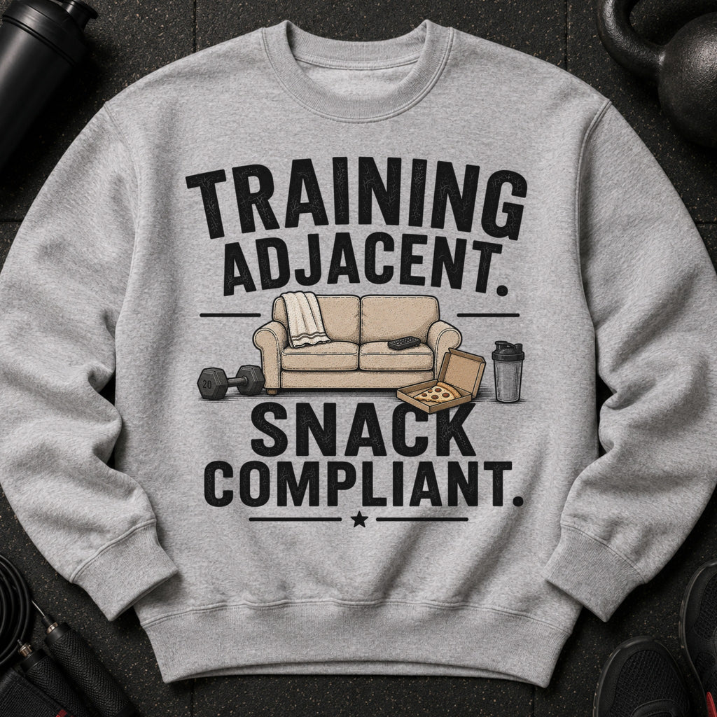 Grey sweatshirt with "Training Adjacent. Snack Compliant." text, sofa, pizza, and weights.