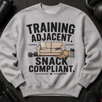 Grey sweatshirt with "Training Adjacent. Snack Compliant." text, sofa, pizza, and weights.
