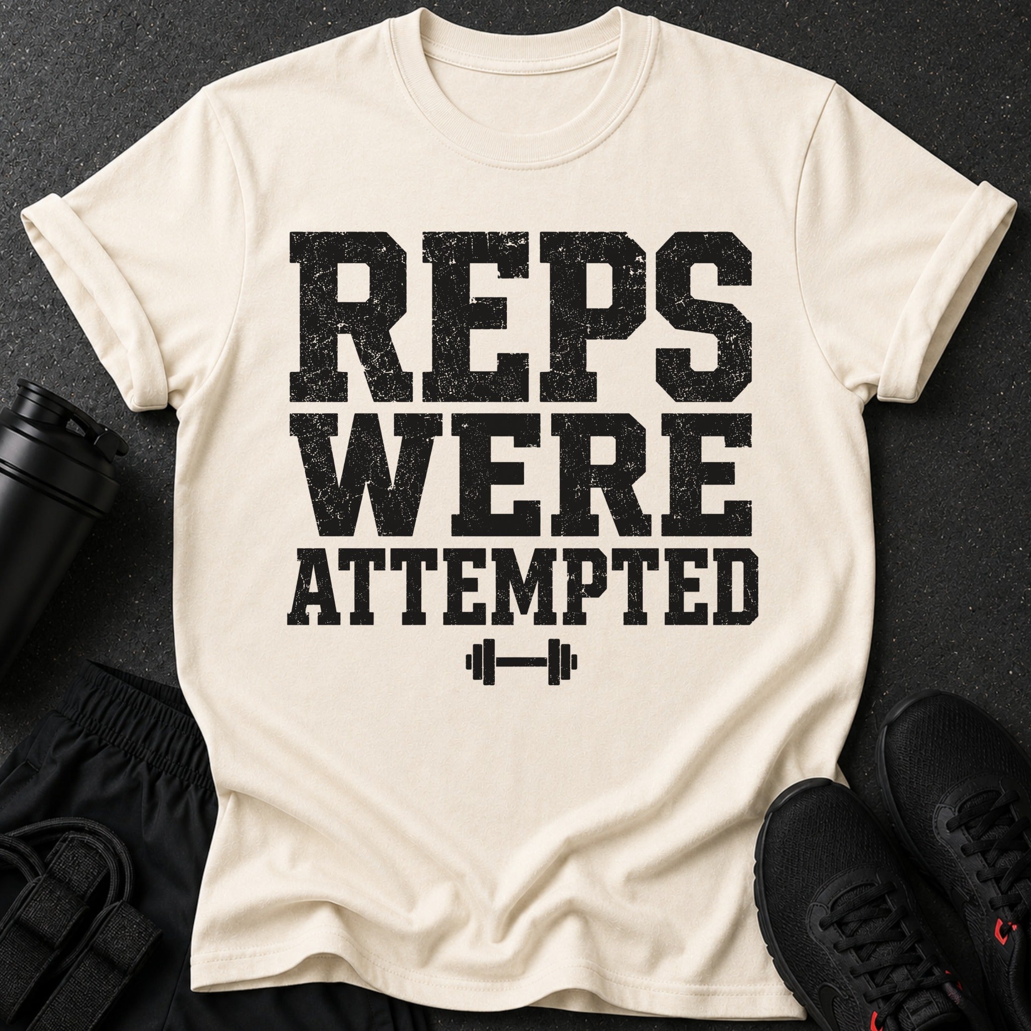 Light cream t-shirt with black distressed text "REPS WERE ATTEMPTED" and barbell graphic.