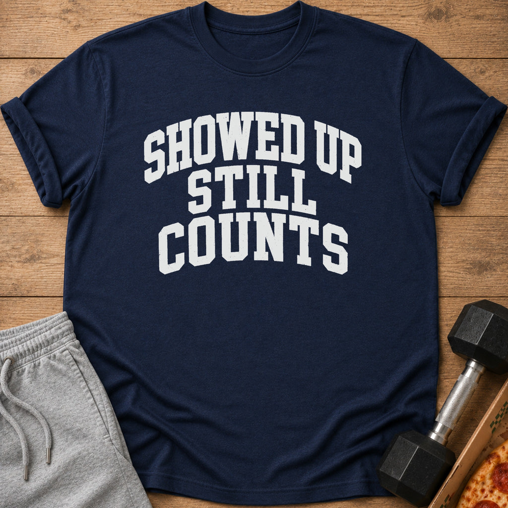 Navy t-shirt with white text "SHOWED UP STILL COUNTS" next to shorts and a dumbbell.