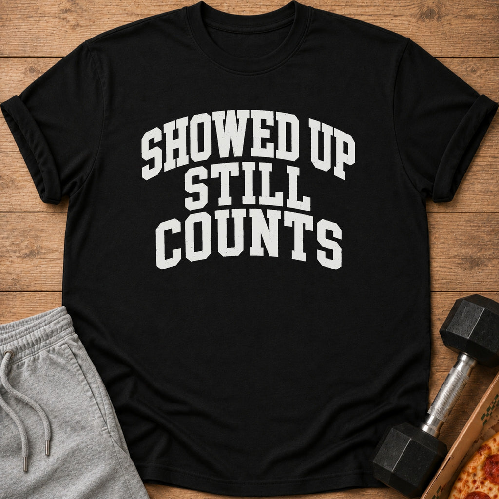 Black t-shirt with text "SHOWED UP STILL COUNTS" and athletic wear.
