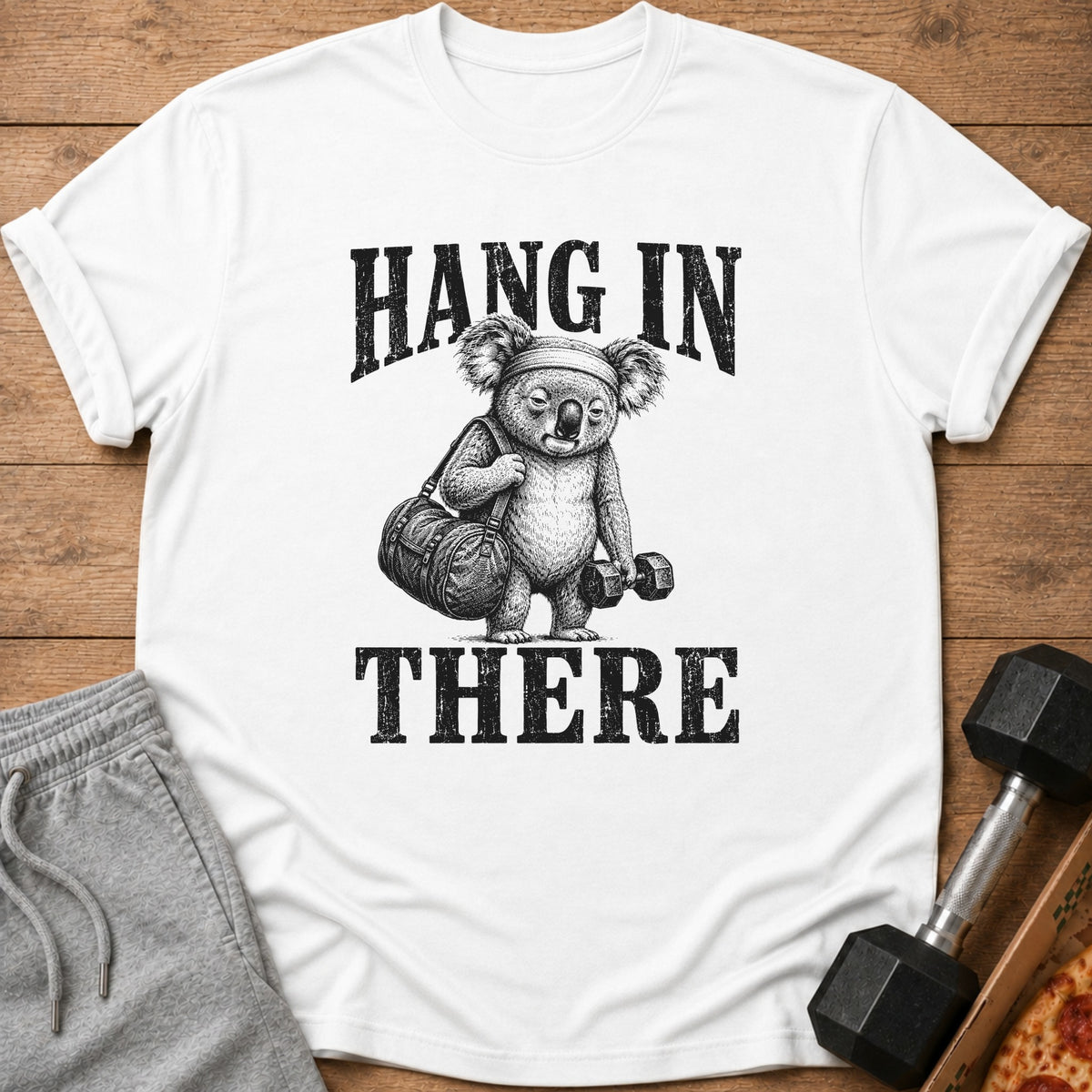 White t-shirt with a drawing of a koala holding a gym bag and dumbbell, text says "HANG IN THERE".
