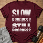 Maroon t-shirt with white text: "SLOW PROGRESS STILL PROGRESS".