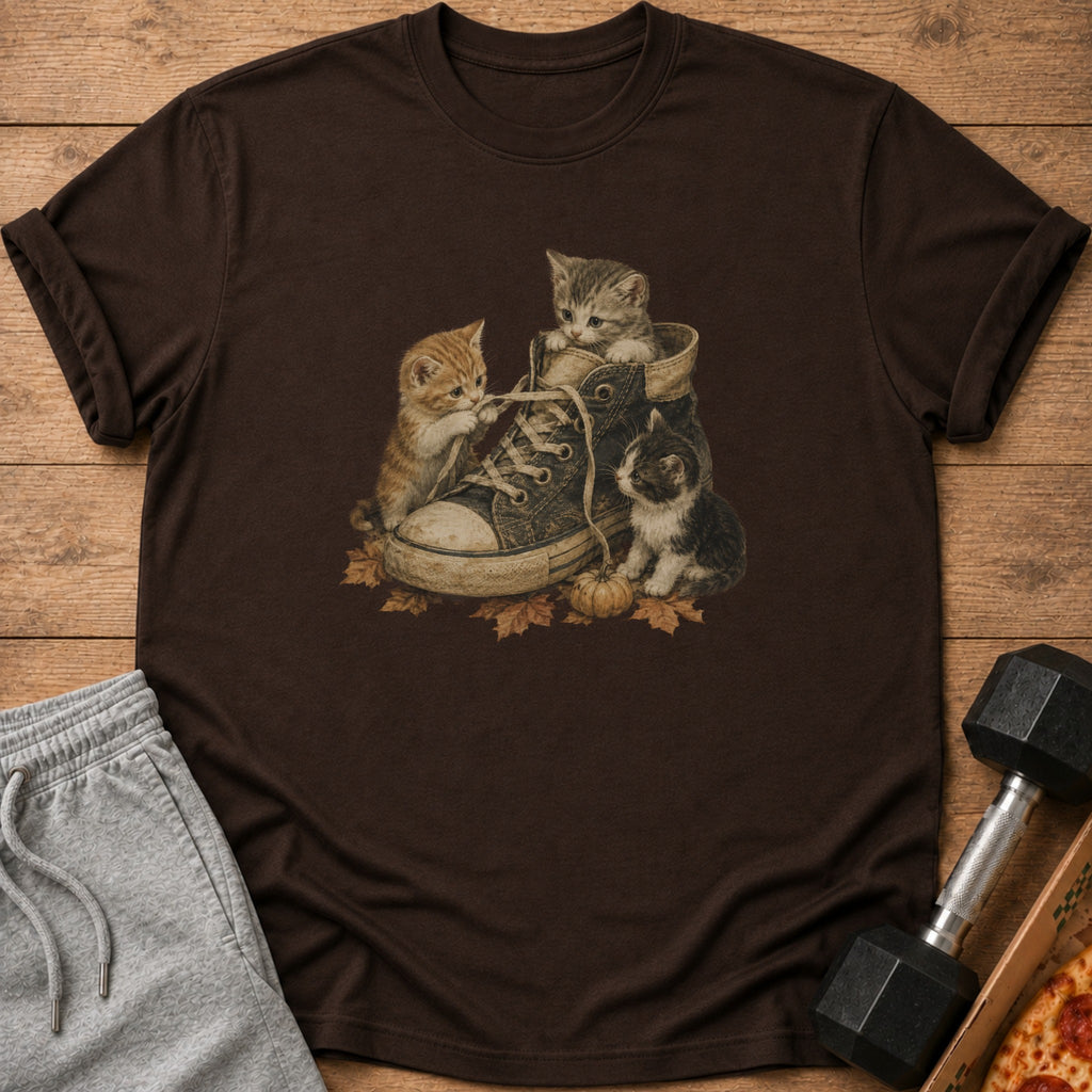 Three kittens play inside a vintage sneaker surrounded by autumn leaves.