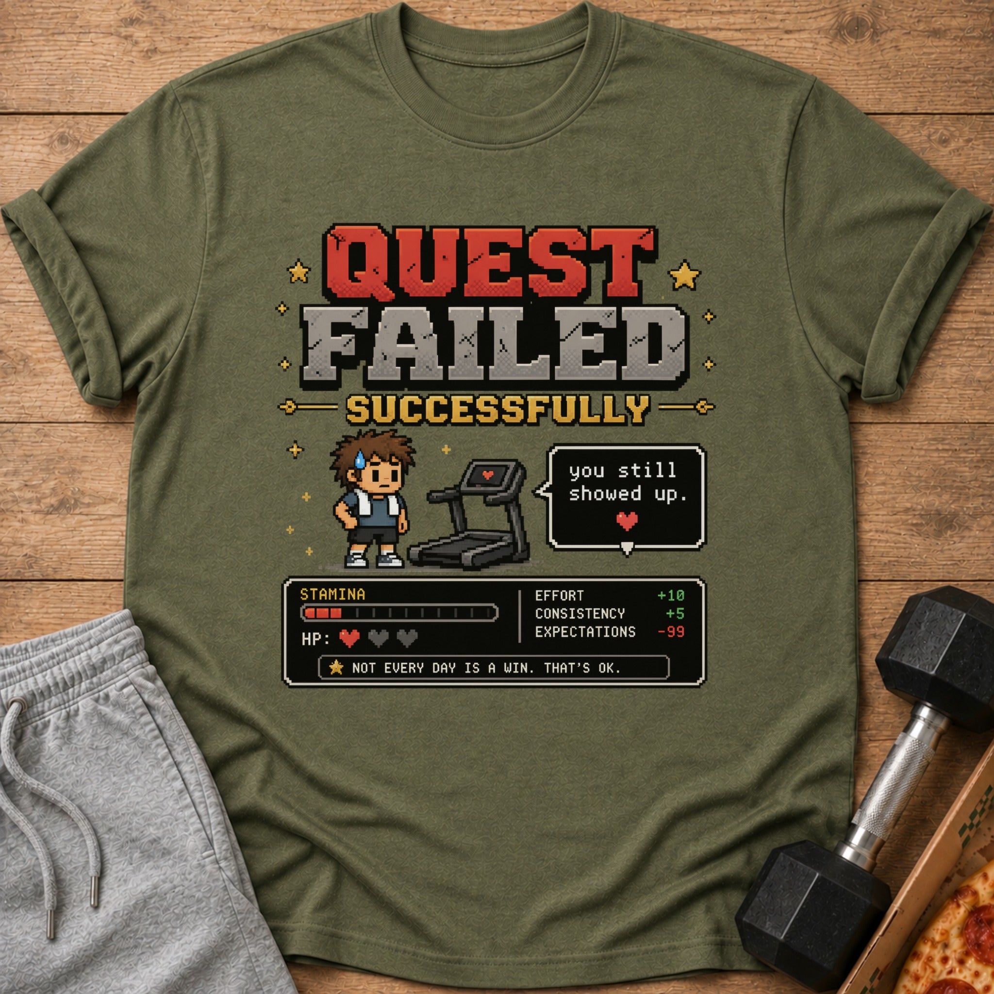 Olive green t-shirt with "QUEST FAILED SUCCESSFULLY" pixel art.